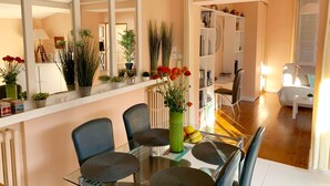 A modern living room with a glass dining table, two chairs, a bookshelf, and a large mirror. - House / Villa - La rochelle (La Rochelle)