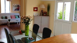 A dining area with a glass table, chairs, a white cabinet, and a sofa with cushions. - House / Villa - La rochelle (La Rochelle)
