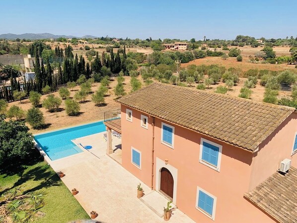 Un edificio de dos pisos con piscina, rodeado de árboles y un paisaje montañoso.