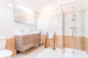 Une salle de bain moderne avec un meuble-lavabo en bois, une cabine de douche en verre et un grand miroir.