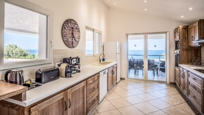A modern kitchen with a large window, a clock, and a view of the sea.