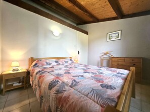 A bedroom with a bed, bedside tables, a dresser, a ceiling fan, and a wall-mounted light fixture.