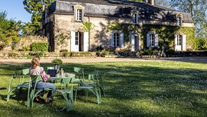 A stone building with a garden patio, outdoor seating, and a view of the surrounding landscape.