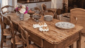A dining room with a wooden table, chairs, a chandelier, and a fireplace.