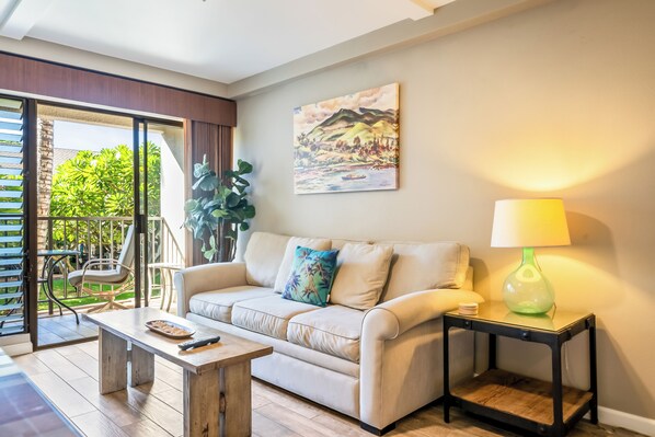 A living room with a sofa, a coffee table, a lamp, and a painting on the wall.