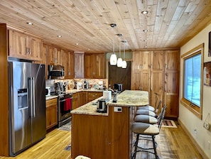 A kitchen with wooden cabinets, stainless steel appliances, a granite countertop, and a bar stool. - Hauser's Bayfield Cabin (Whole Cabin) (Bayfield)