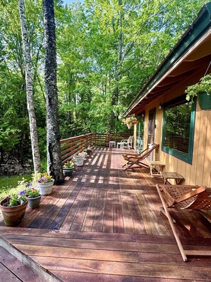 A wooden deck with outdoor furniture, surrounded by trees.