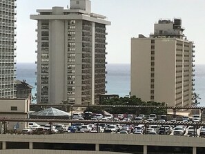 Un estacionamiento con varios autos y edificios altos al fondo.