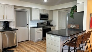 Une cuisine moderne avec des meubles blancs, des appareils en acier inoxydable et un plancher en bois.