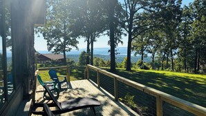 Une terrasse en bois, agréée de mobilier d’extérieur, qui offre une vue sur un paysage verdoyant et luxuriant ainsi que sur des montagnes lointaines.