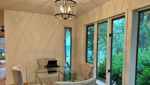 Une pièce moderne avec une table en verre, deux fauteuils rembourrés, un ordinateur portable et un lustre.