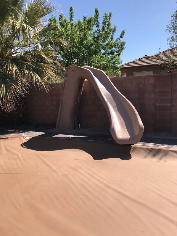 A slide in a backyard with a brick wall and palm trees in the background. - STUNNING/IMMACULATE4bd/2ba PrivatePool/WaterSLIDE new beds!!BOOK (Washington)