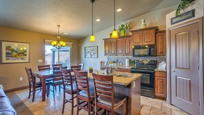 A kitchen with wooden cabinets, a central island with bar stools, pendant lighting, and a built-in microwave. - STUNNING/IMMACULATE4bd/2ba PrivatePool/WaterSLIDE new beds!!BOOK (Washington)