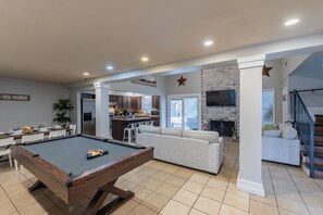 A spacious living area with a pool table, a sofa, and a fireplace. - Private Pool, Mini Golf, Game Room & Fire Pit near Six Flags (San Antonio)