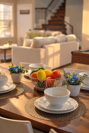 A dining table set with white plates, bowls, and a fruit basket. - Private Pool, Mini Golf, Game Room & Fire Pit near Six Flags (San Antonio)