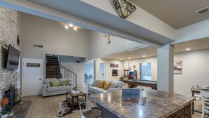 A spacious living area with a fireplace, a pool table, and a game room. - Private Pool, Mini Golf, Game Room & Fire Pit near Six Flags (San Antonio)