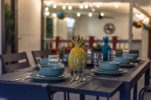 A dining table set with blue plates, bowls, and clear glasses, with a pineapple centerpiece. - Private Pool, Mini Golf, Game Room & Fire Pit near Six Flags (San Antonio)