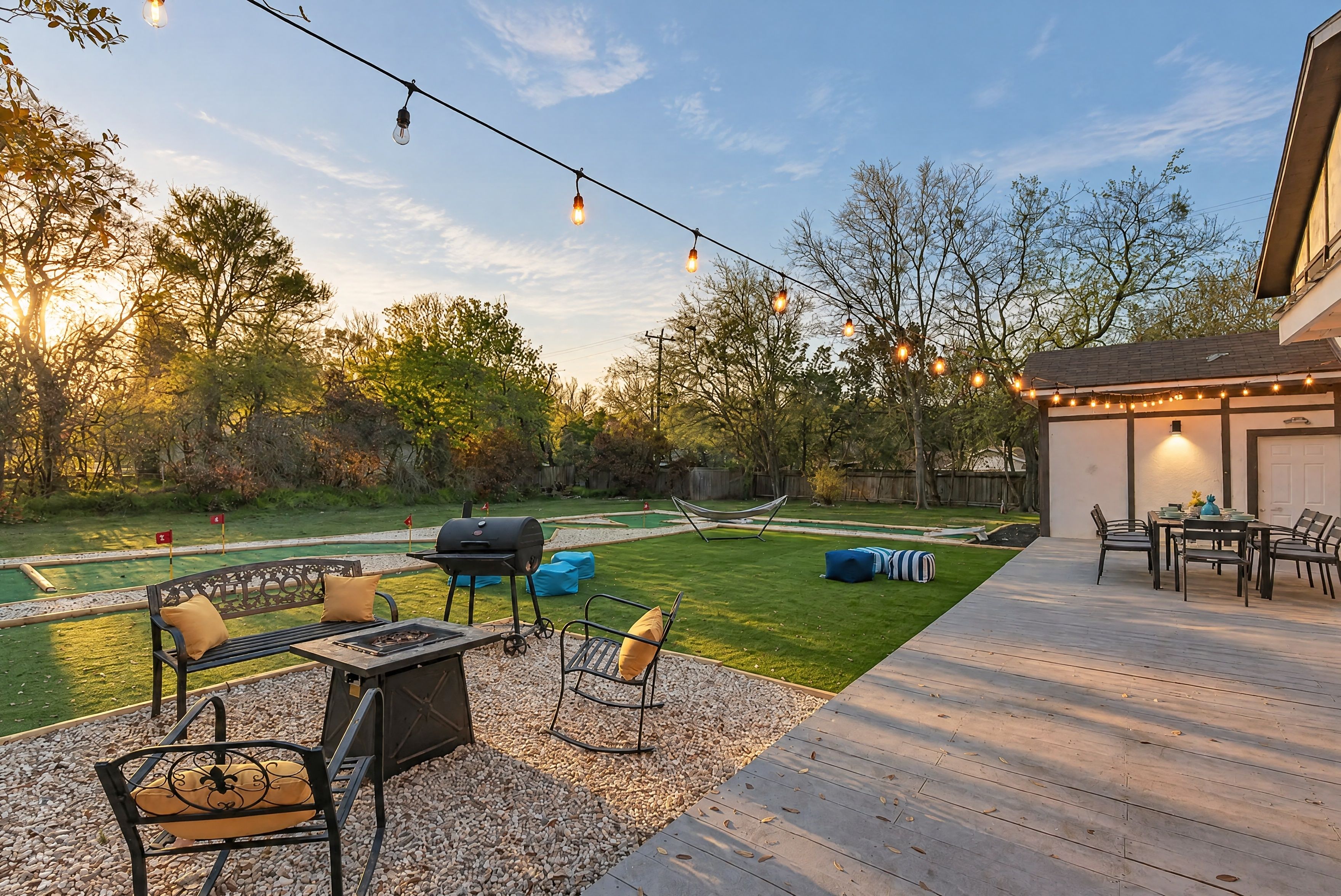 Un patio al aire libre con una parrilla, asientos e iluminación colgante.