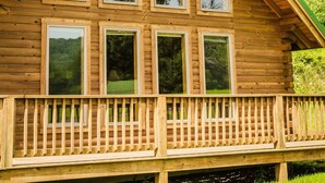 Een houten chalet met een groen dak, grote ramen en een houten terras.