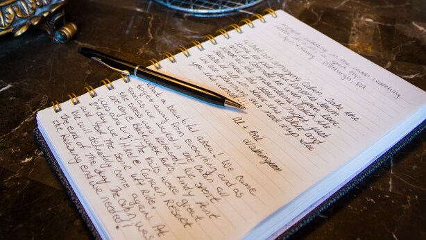 A notebook with handwritten text, a pen, and decorative items on a table. - ✧King Cabin - find out why it is the KING! (Dryfork)