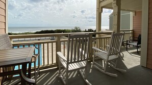 Uma varanda com vista para o oceano, uma piscina e mobiliário de exterior.