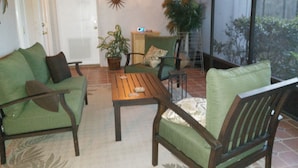 Un salon avec un canapé vert, une table basse en bois et un ventilateur de plafond.