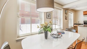 Una cocina moderna con encimera blanca, una lámpara colgante y un florero con flores sobre la mesa.