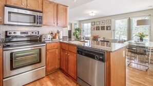 Una cocina moderna con armarios de madera, electrodomésticos de acero inoxidable y una isla central con taburetes de bar.