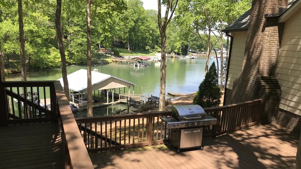Eine Terrasse mit Grill, mit Blick auf einen See mit Booten und einem Steg.