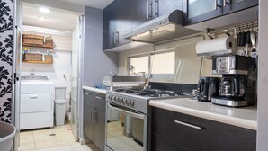 Una cocina compacta con estufa a gas, horno y cafetera.