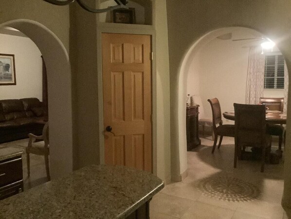Una sala acogedora con una puerta de madera, una mesa de comedor con sillas y una encimera de cocina.