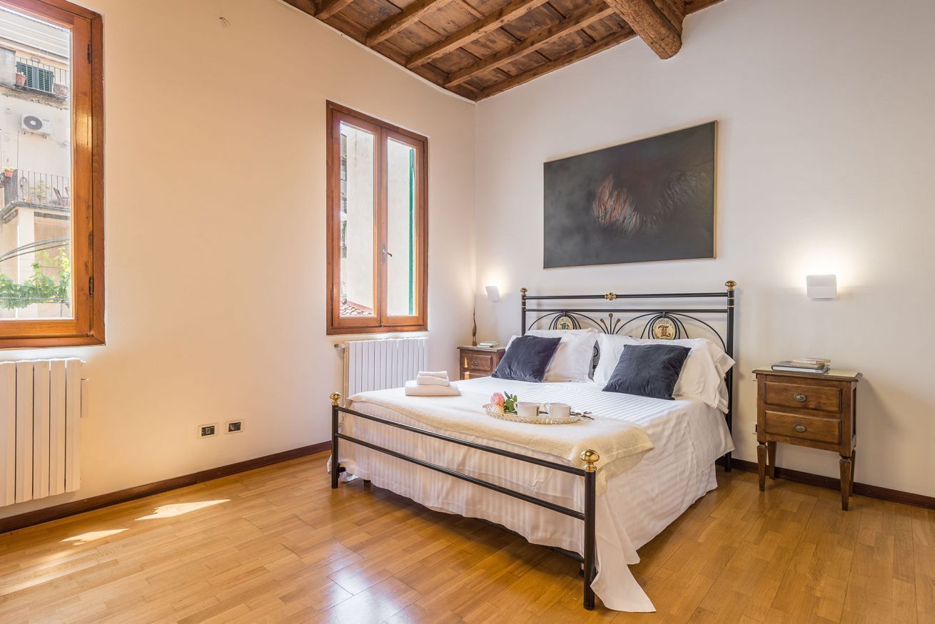 Quarto com cama, radiador, janela, pintura e mesa de cabeceira.
