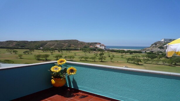 A pool with a view of a golf course and a building in the distance.