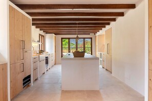 Una cocina moderna con armarios de madera, una isla central y vistas a zonas verdes.