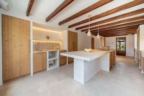 A modern kitchen with wooden beams, a central island, and a view to the outdoors.
