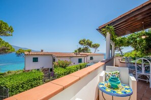 A balcony with a view of the sea, white buildings, and a table with a decorative bowl. - Villa with private beach access (capoliveri Isola d'Elba)