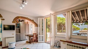 Un vaste espace de vie comprenant une table à manger, un téléviseur et une vue sur la mer.