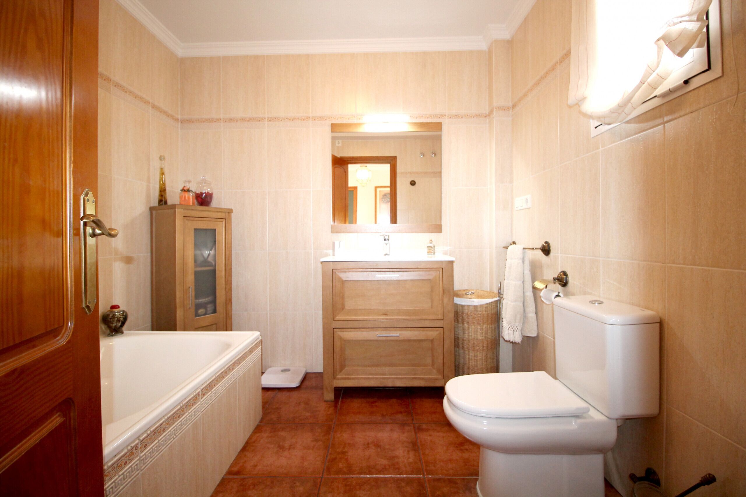 A bathroom with a bathtub, toilet, vanity, and a mirror.