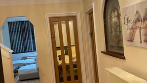 A hallway with a wooden floor, a chandelier, a door with glass panels, and a wall-mounted light fixture. - 8 Bedroom mansion.Private Gated FreeSauna hottub sleep 15-23 Marble Park 12 cars (Luton)