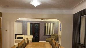 A dining room with a long wooden table and chairs, a ceiling fan, and a chandelier. - 8 Bedroom mansion.Private Gated FreeSauna hottub sleep 15-23 Marble Park 12 cars (Luton)