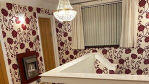 A room with a wooden floor, a chandelier, a fireplace, and floral wallpaper. - 8 Bedroom mansion.Private Gated FreeSauna hottub sleep 15-23 Marble Park 12 cars (Luton)