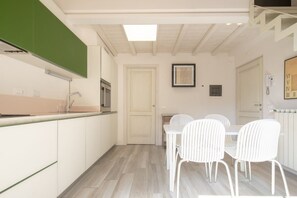 Una cucina compatta con zona pranzo, una porta bianca e un quadro appeso al muro.