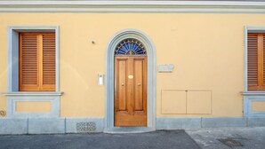 Un bâtiment avec une porte en bois, une fenêtre avec des volets et une petite plaque sur le mur.