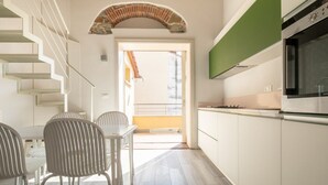 Une cuisine moderne avec des meubles blancs, un mur d’accent vert et un four encastré.