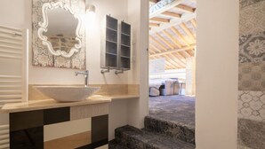 Une salle de bain avec un lavabo blanc, un miroir et un mur décoré d’un motif.