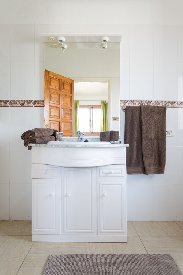 Un baño con tocador blanco, espejo y perchero.