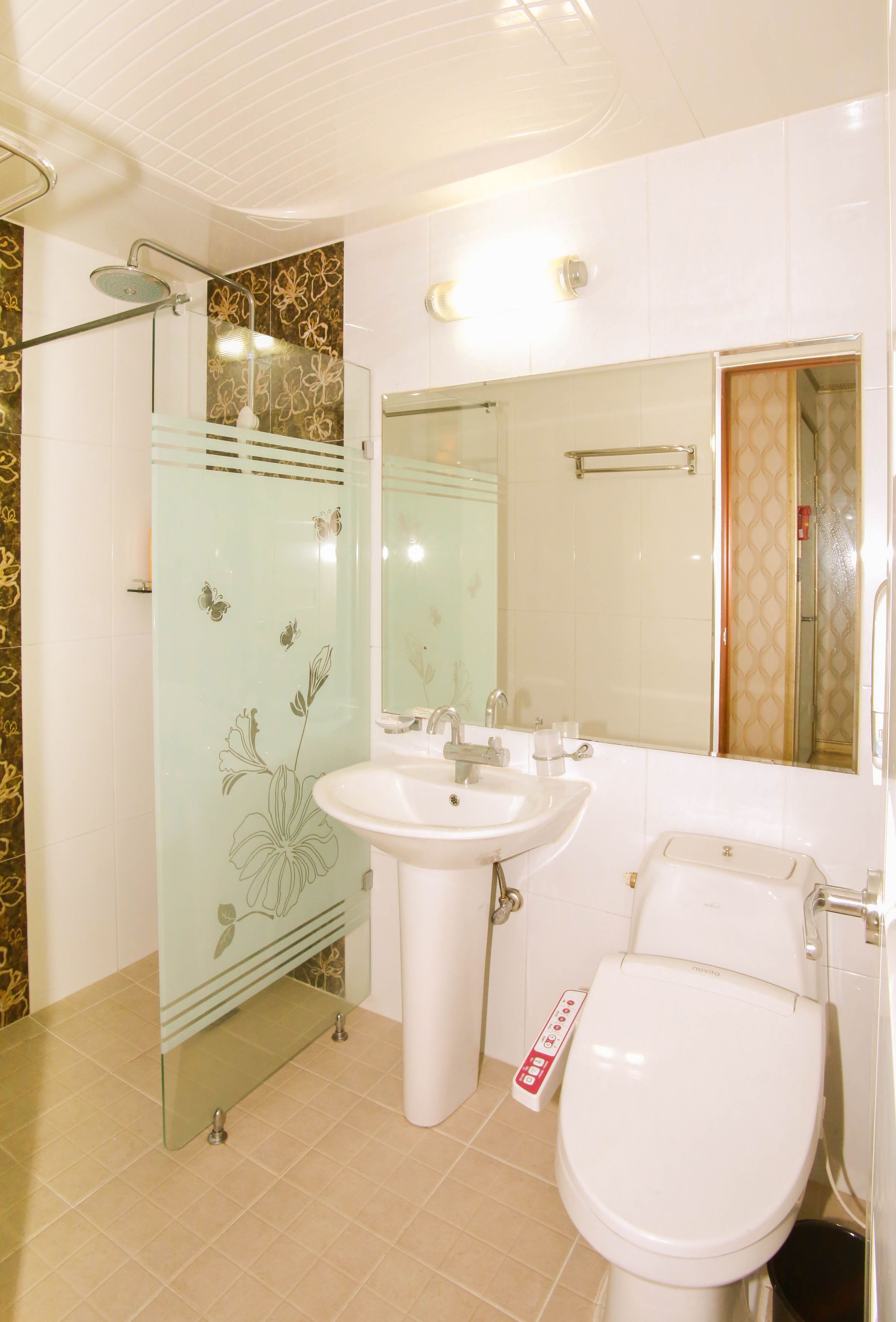 A bathroom with a glass shower enclosure, a sink, a toilet, and a mirror.