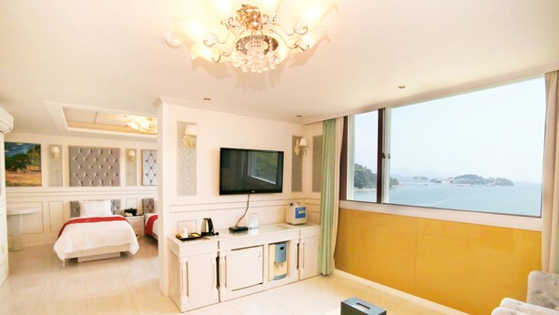 Una habitación de hotel con cama, televisión, escritorio y vistas al mar.