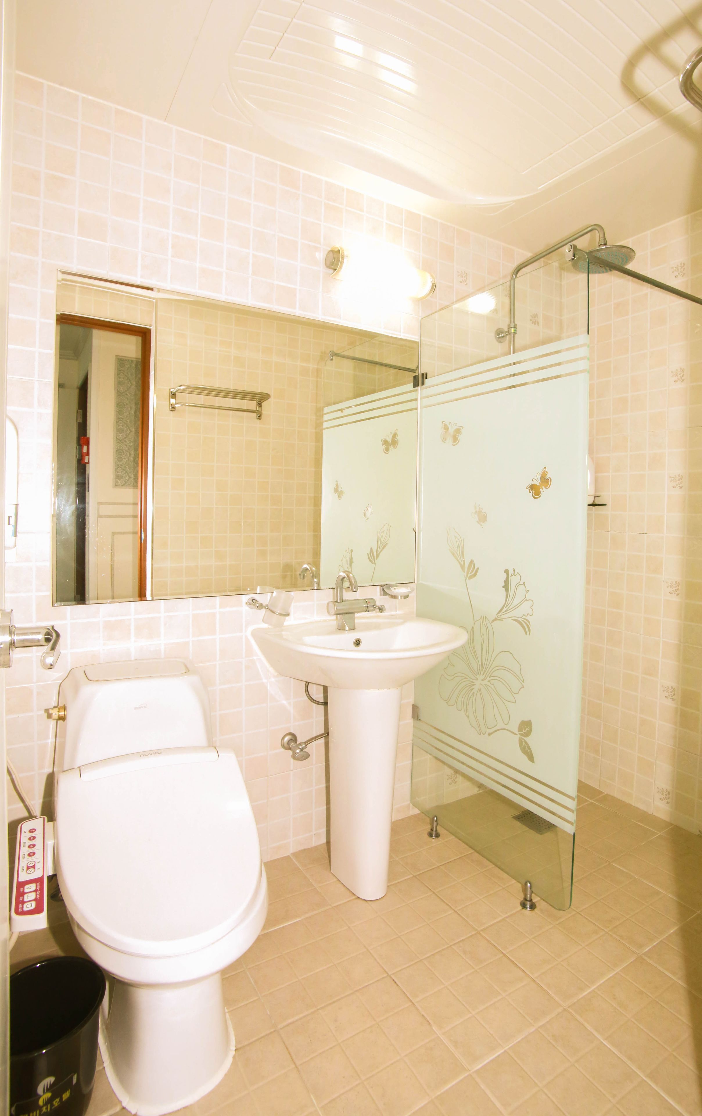 A bathroom with a toilet, sink, and glass shower enclosure.