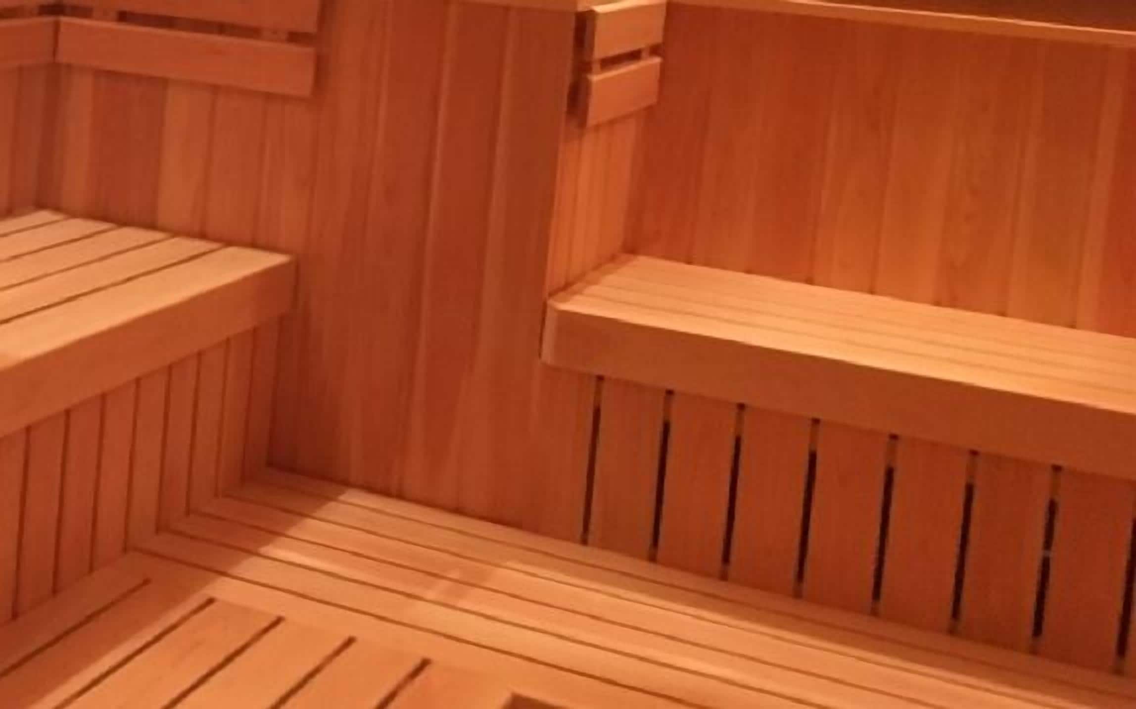 Una sauna de madera con bancos y un banco en el suelo.